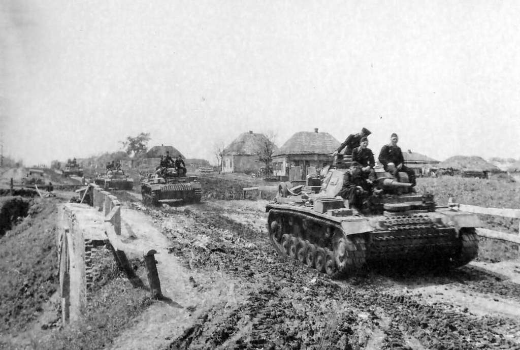 Panzer IIIs crossing a Soviet village in the muddy season